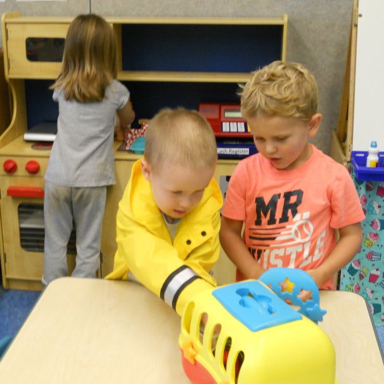 Three children playing with toys in a classroom