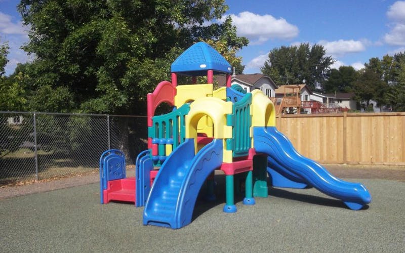 Colorful playground structure with multiple slides on a green mat