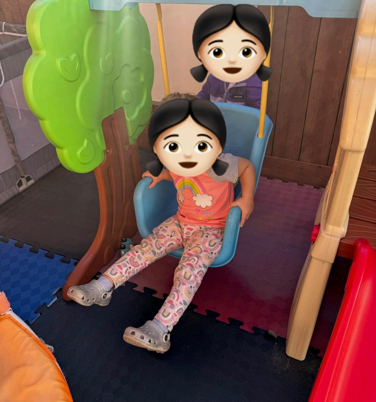 child on a blue swing, another child in background