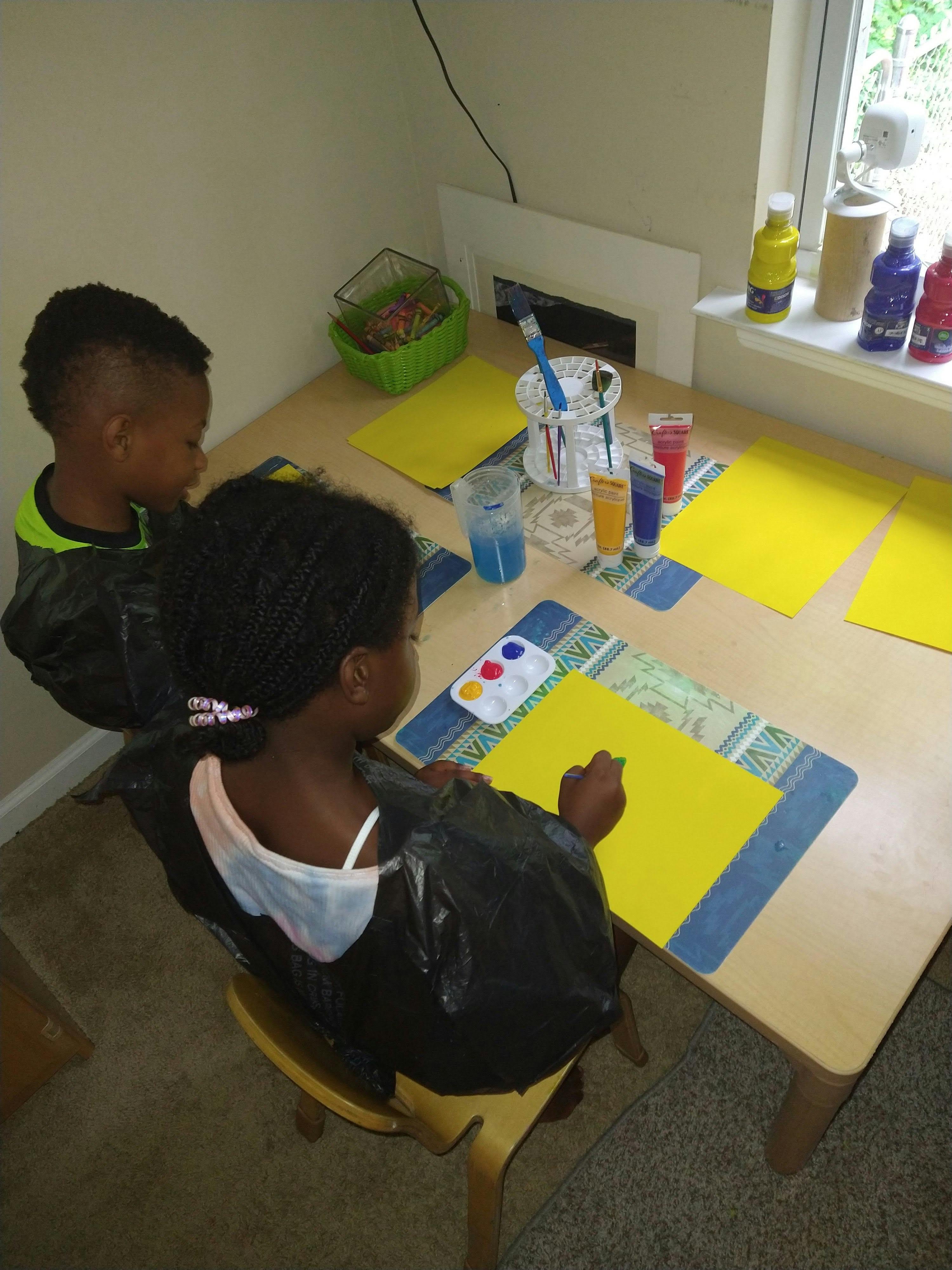 Two children painting at a table