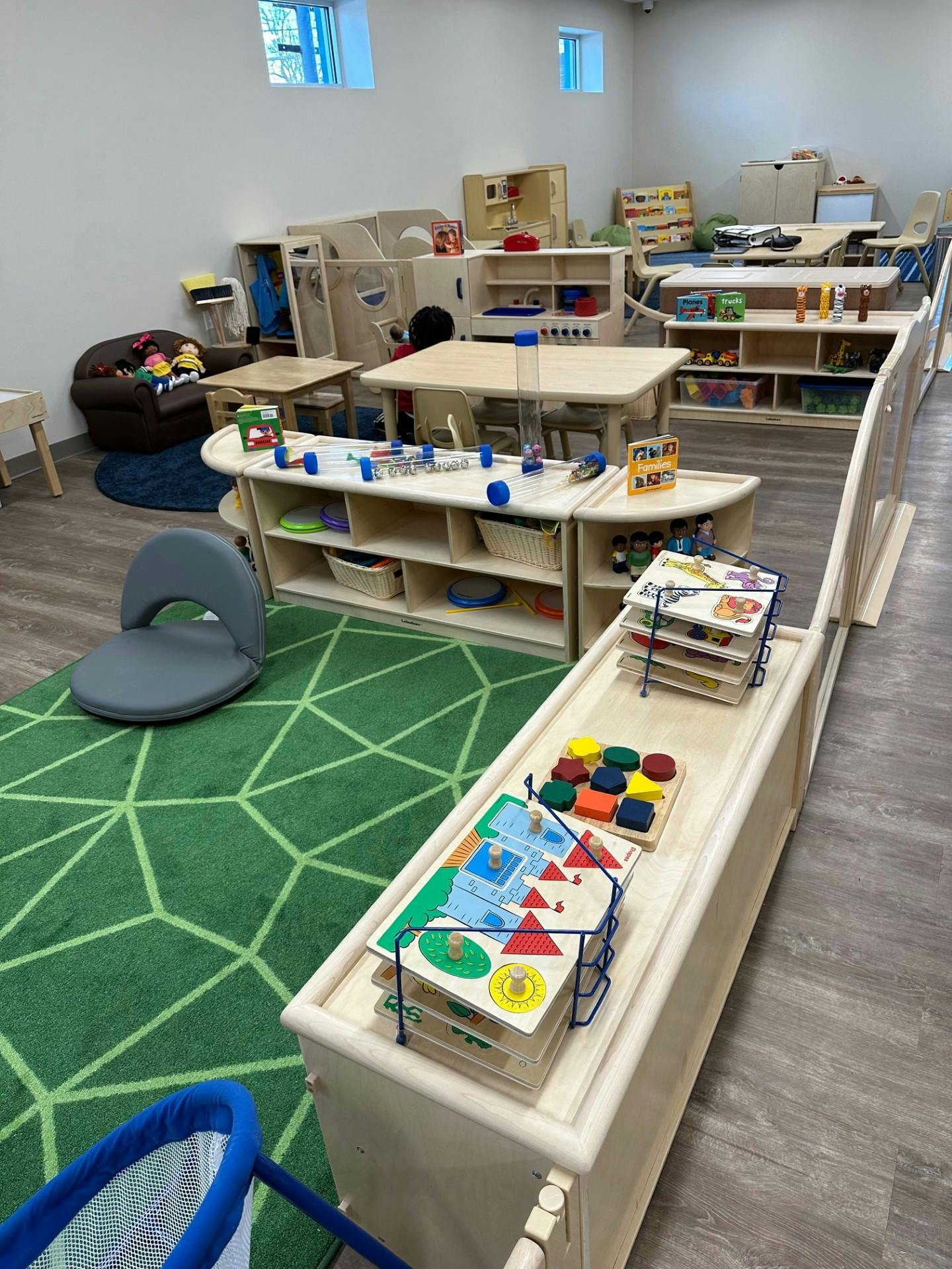 Classroom with small tables, chairs, and shelves with toys and learning materials