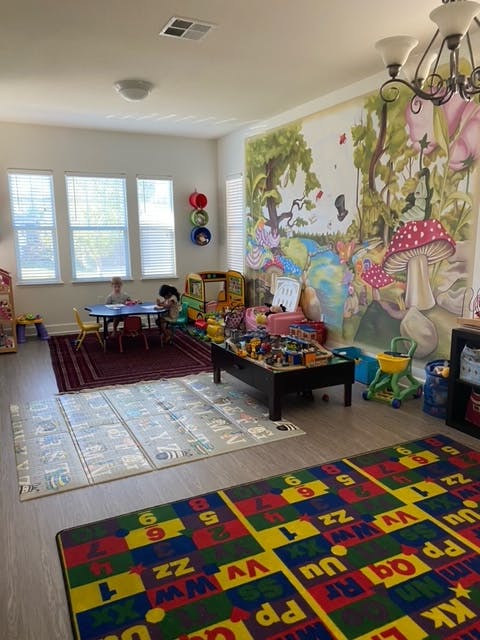 Children playing in a brightly lit room with a mural and toys