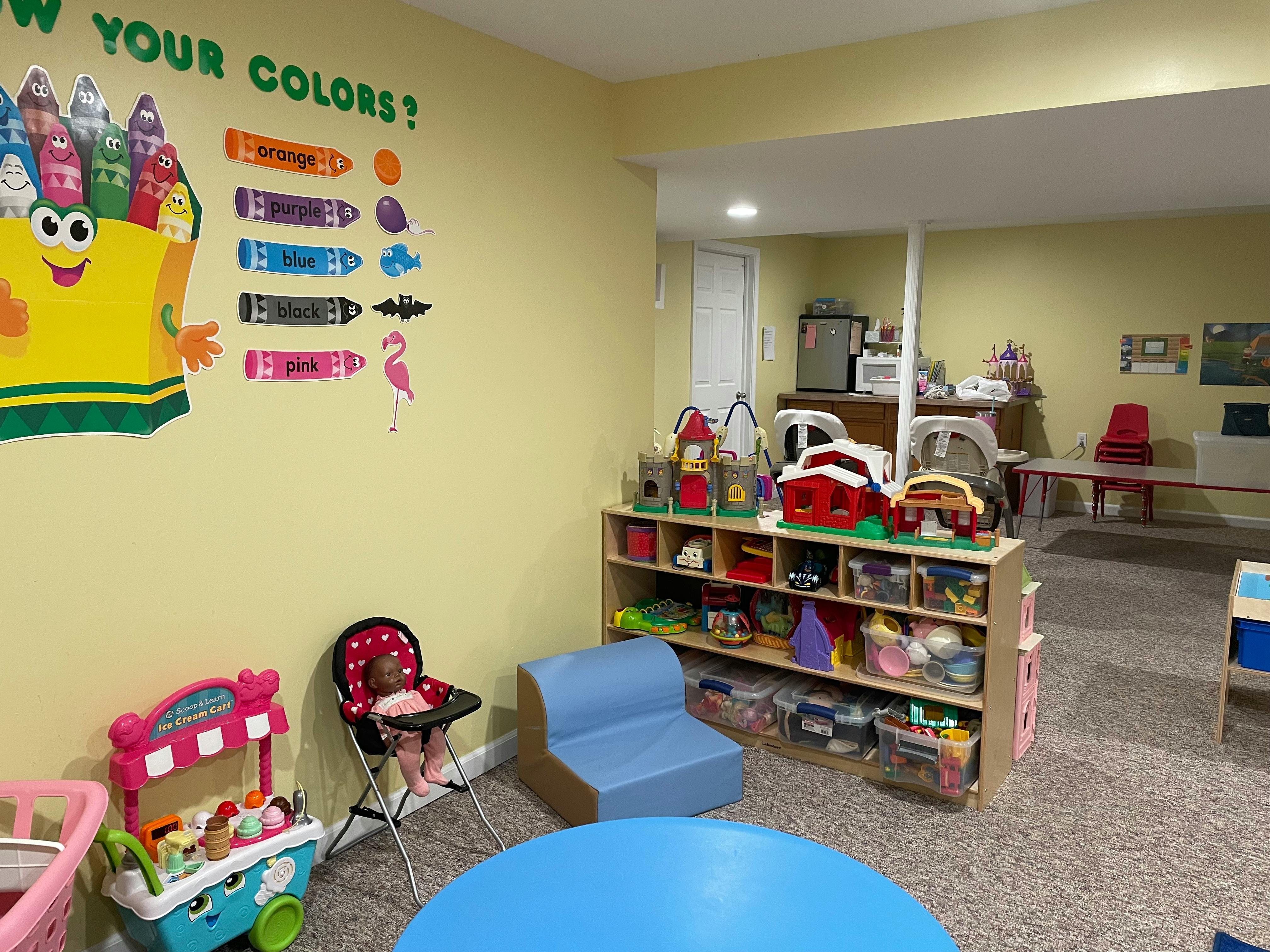Playroom with a crayon wall decal, toy shelf, and small furniture