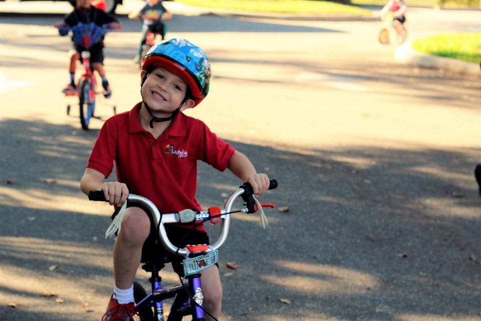 Child in a helmet riding a bicycle on a paved surface