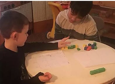 Two children playing with colorful blocks on a table