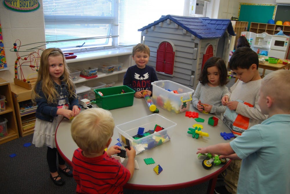 Children playing with building blocks at a table in a classroom