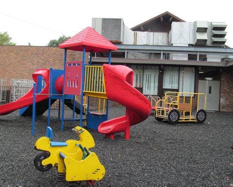 Playground with red and blue slides, yellow spring rider, and yellow play vehicle