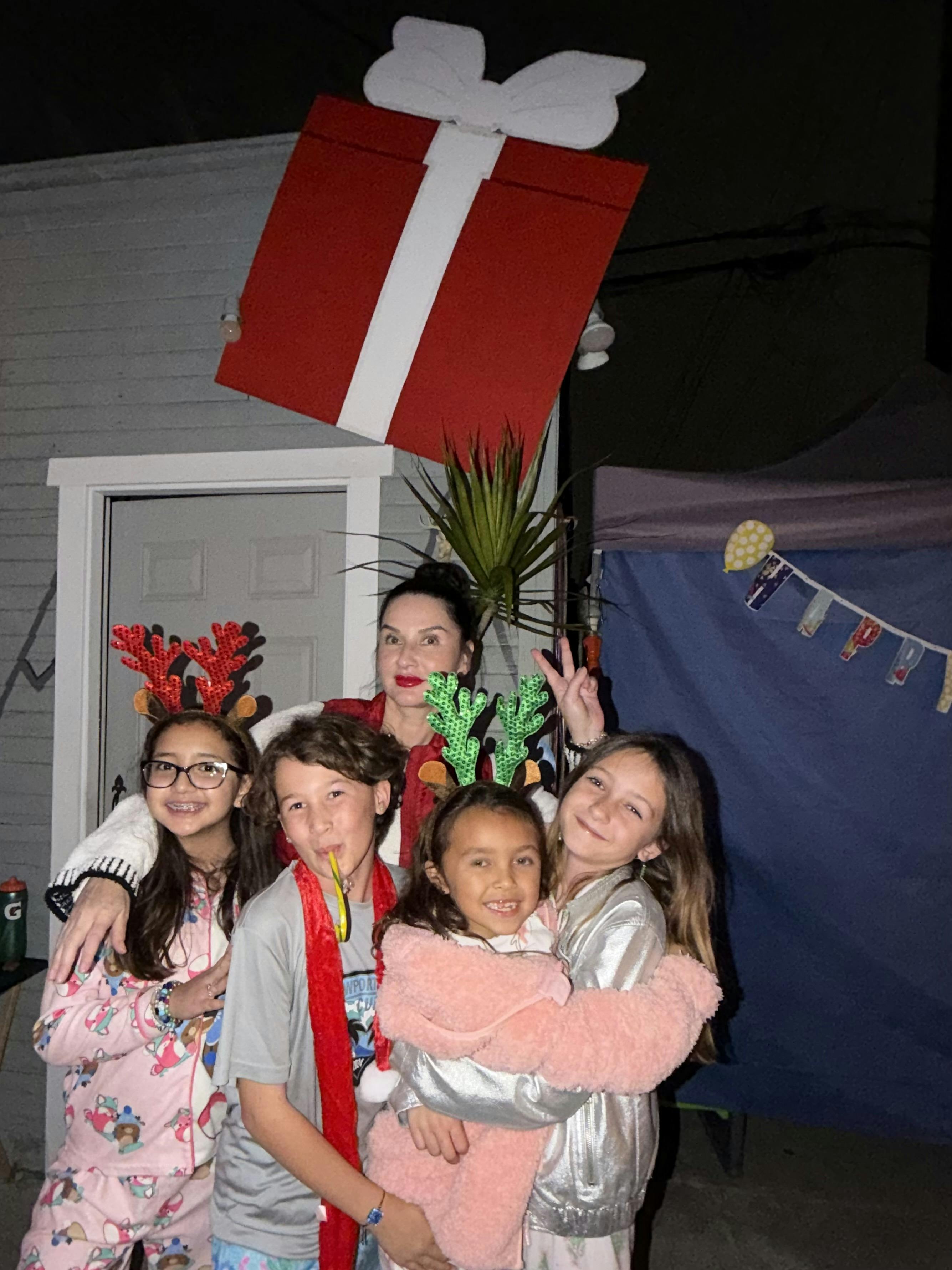 A woman and four children wearing festive headbands and pajamas