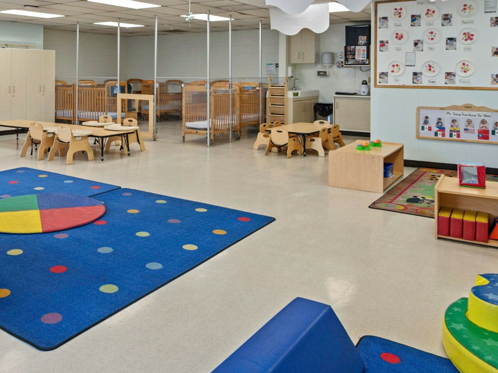 Baby room with multiple cribs, tables, and play mats