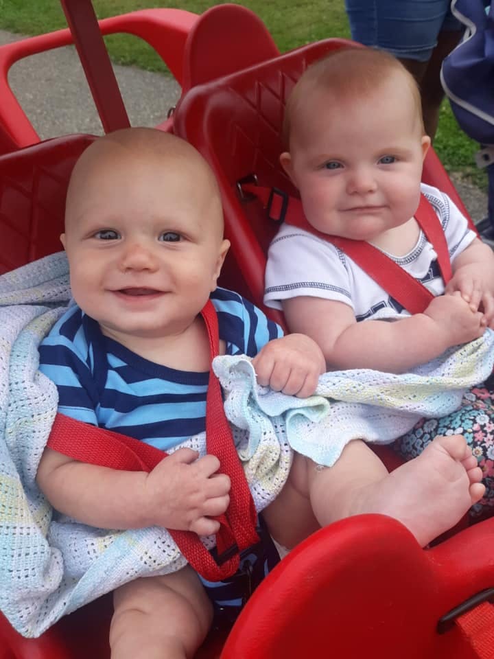 Two babies sitting in a red wagon