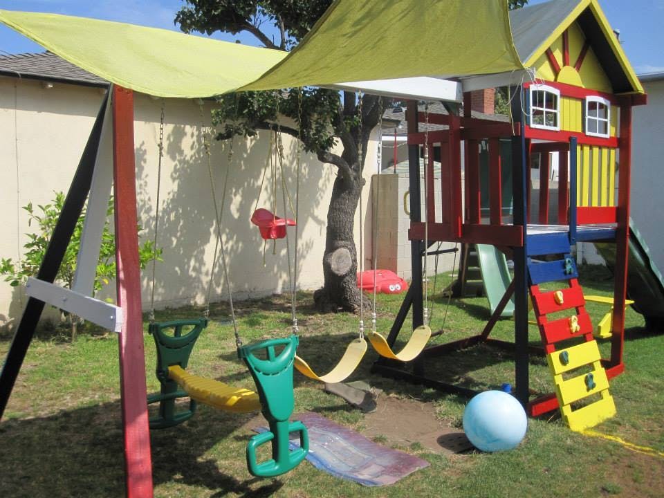 Outdoor playground with swings, slide, and playhouse