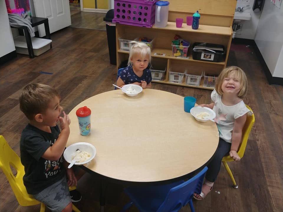Three children sitting at a round table with bowls