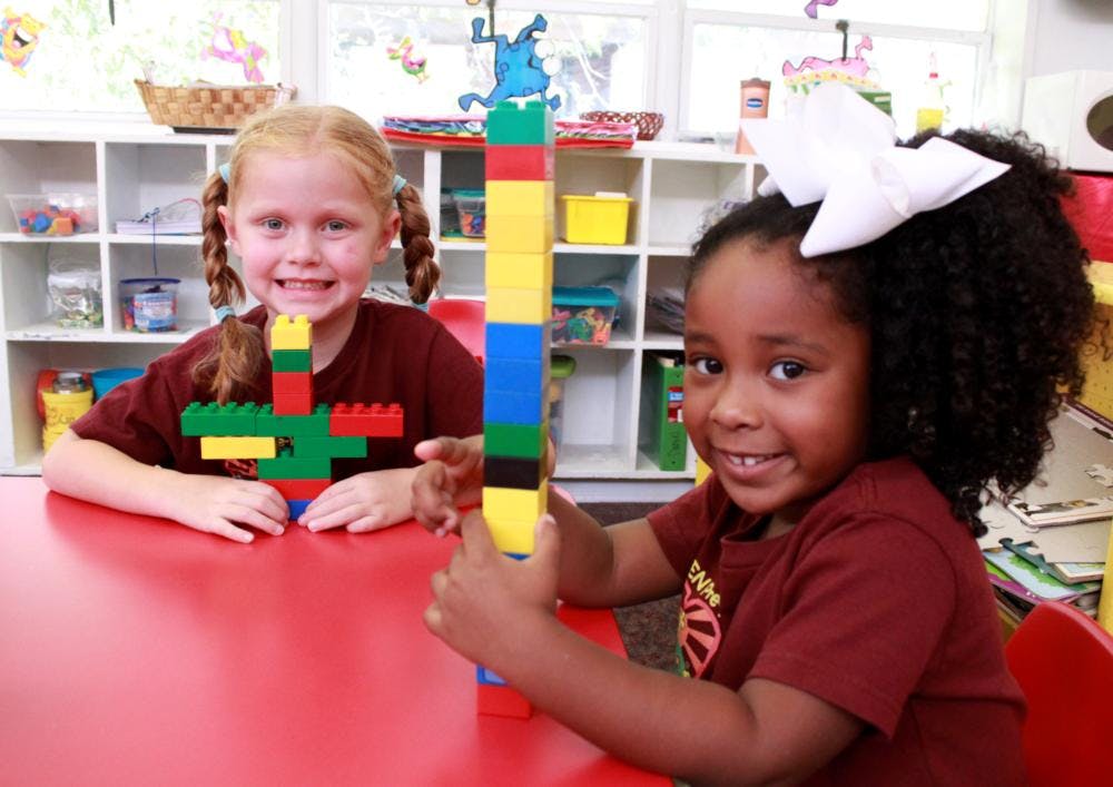 Two children playing with colorful building blocks at a table