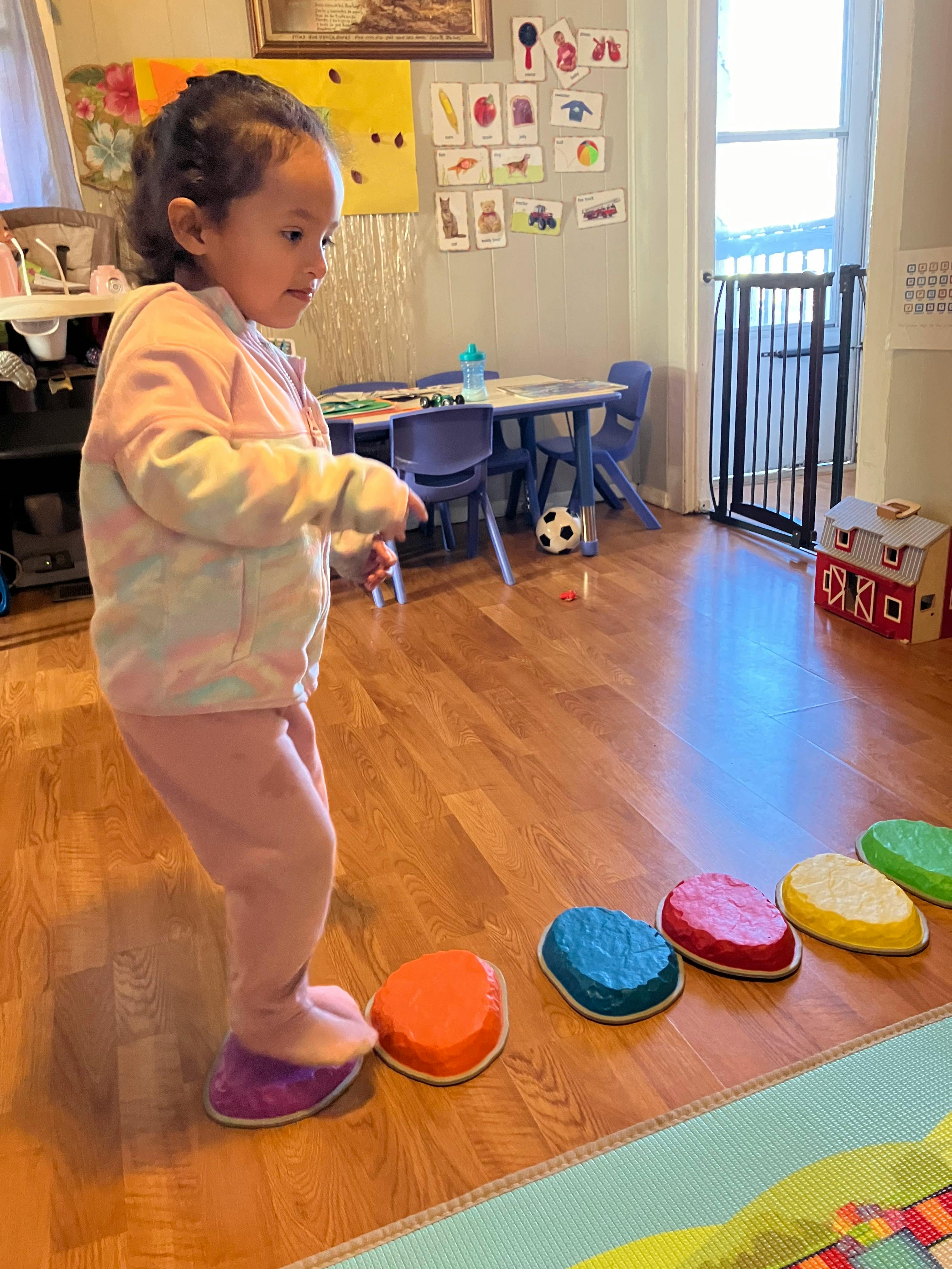 Child stepping on colorful balance stones indoors