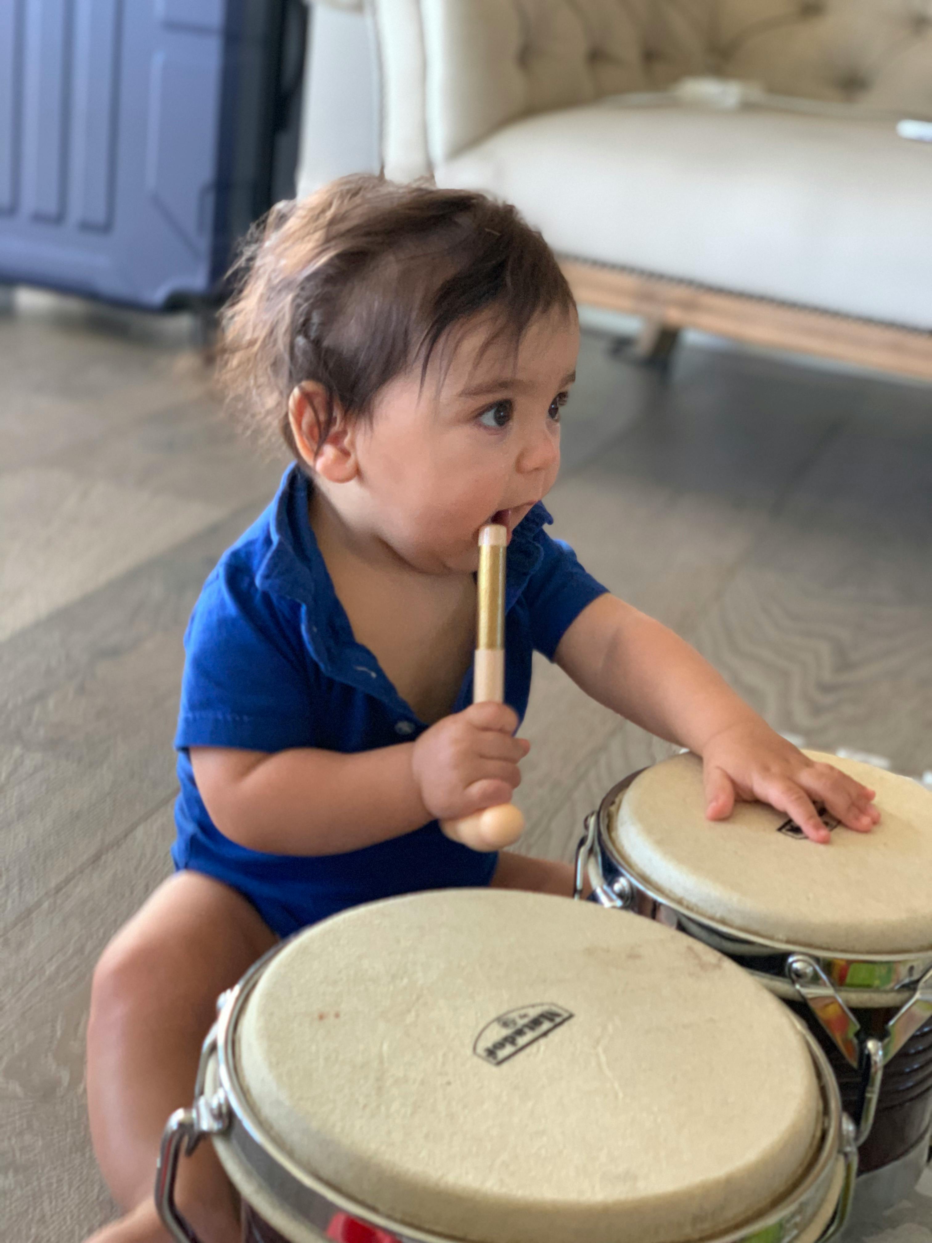 Child playing with bongo drums and a drumstick