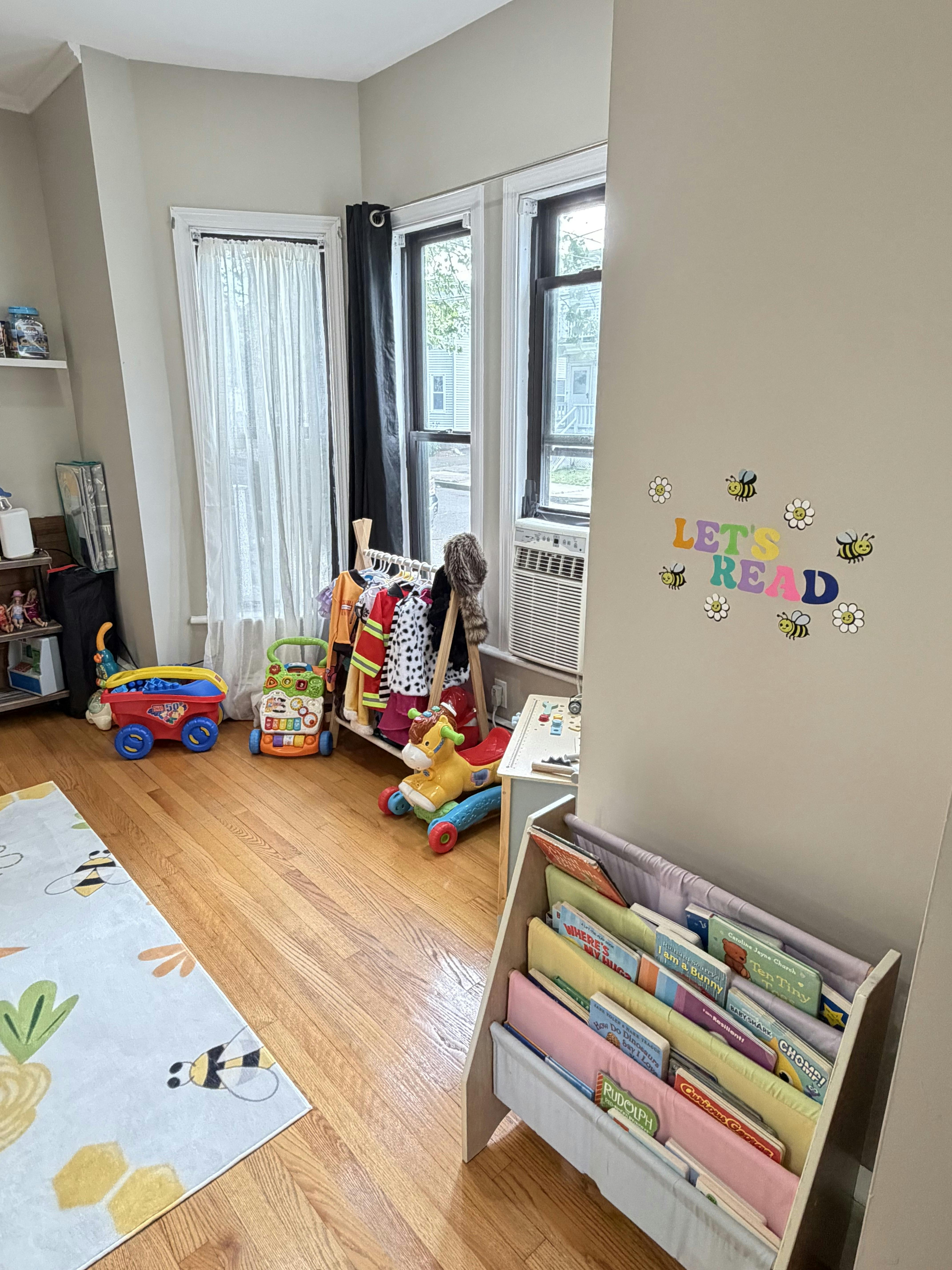 Playroom with a small bookshelf, costumes on a rack, and toys on a wooden floor