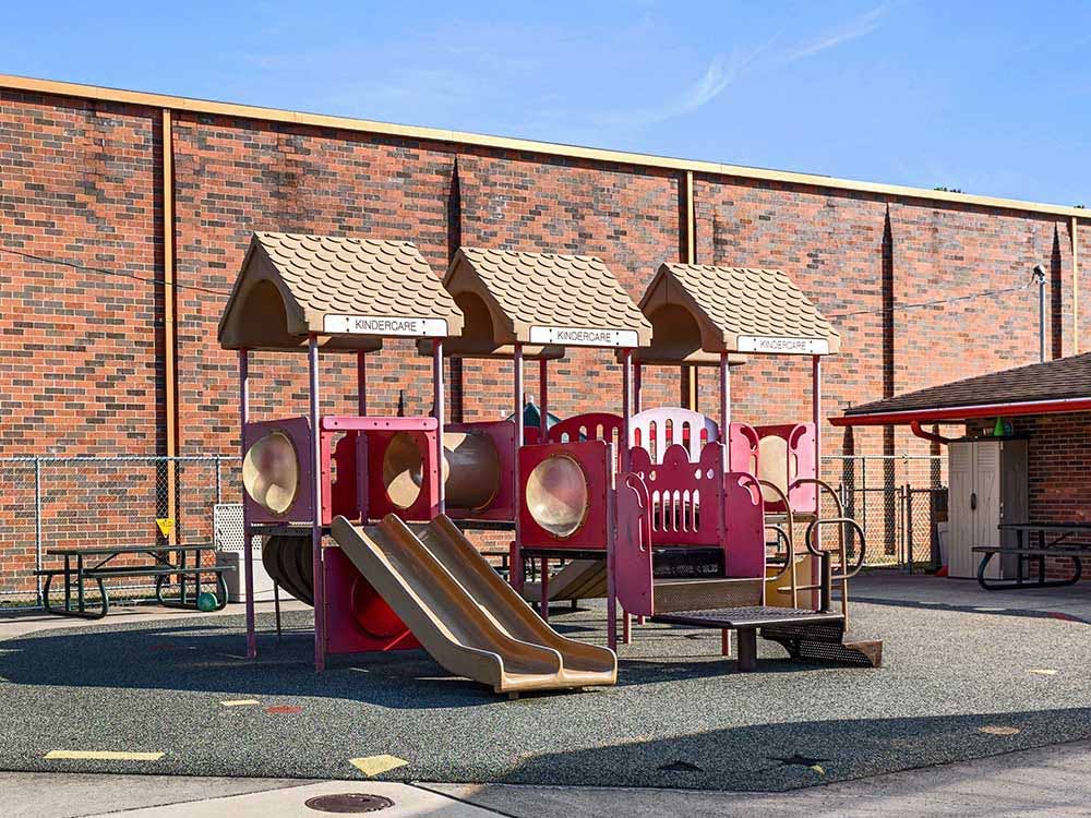 A playground structure with two slides, Kindercare signs, and a picnic table