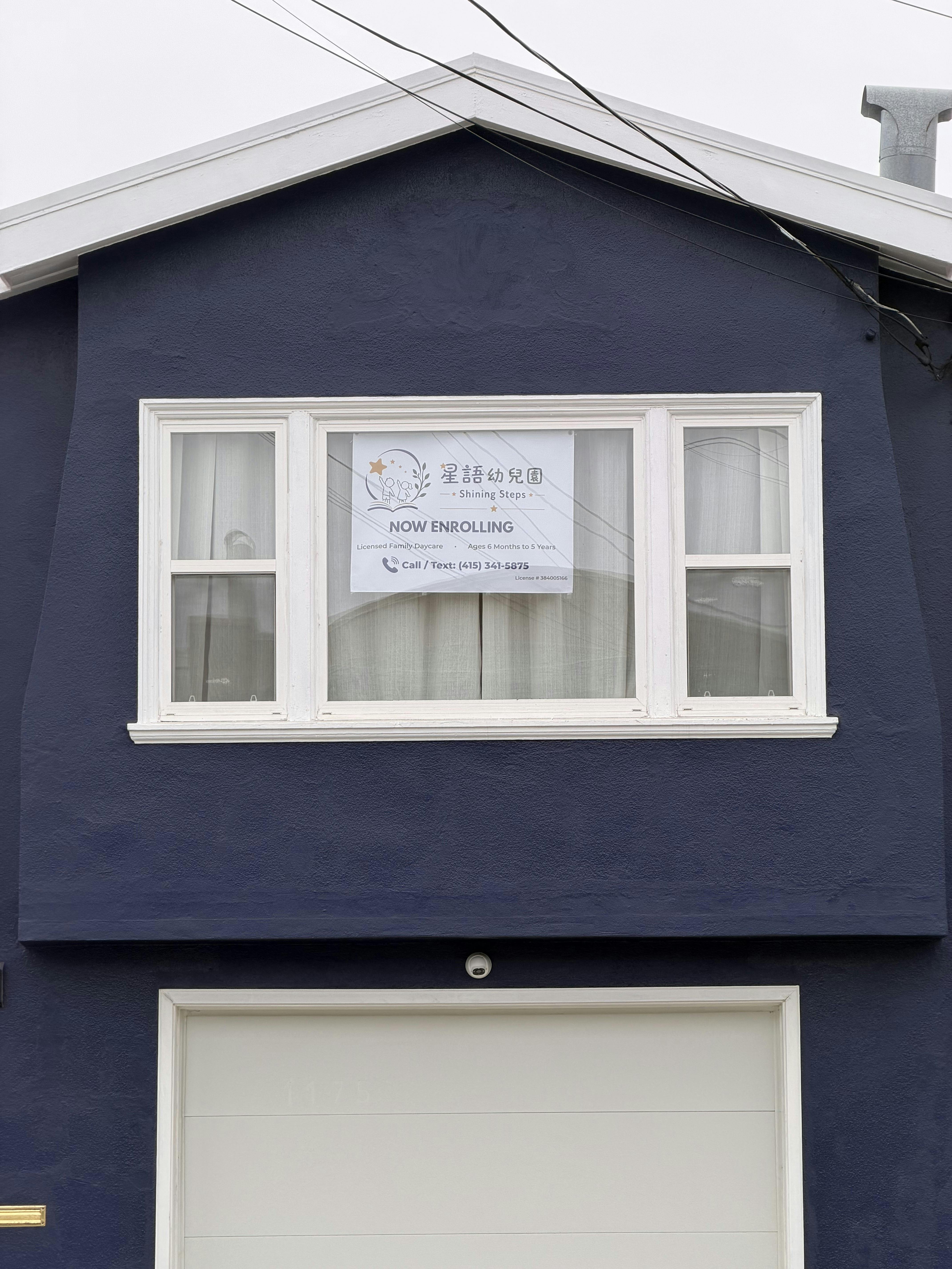 Sign in a window for Shining Steps Daycare, \"Now Enrolling\"