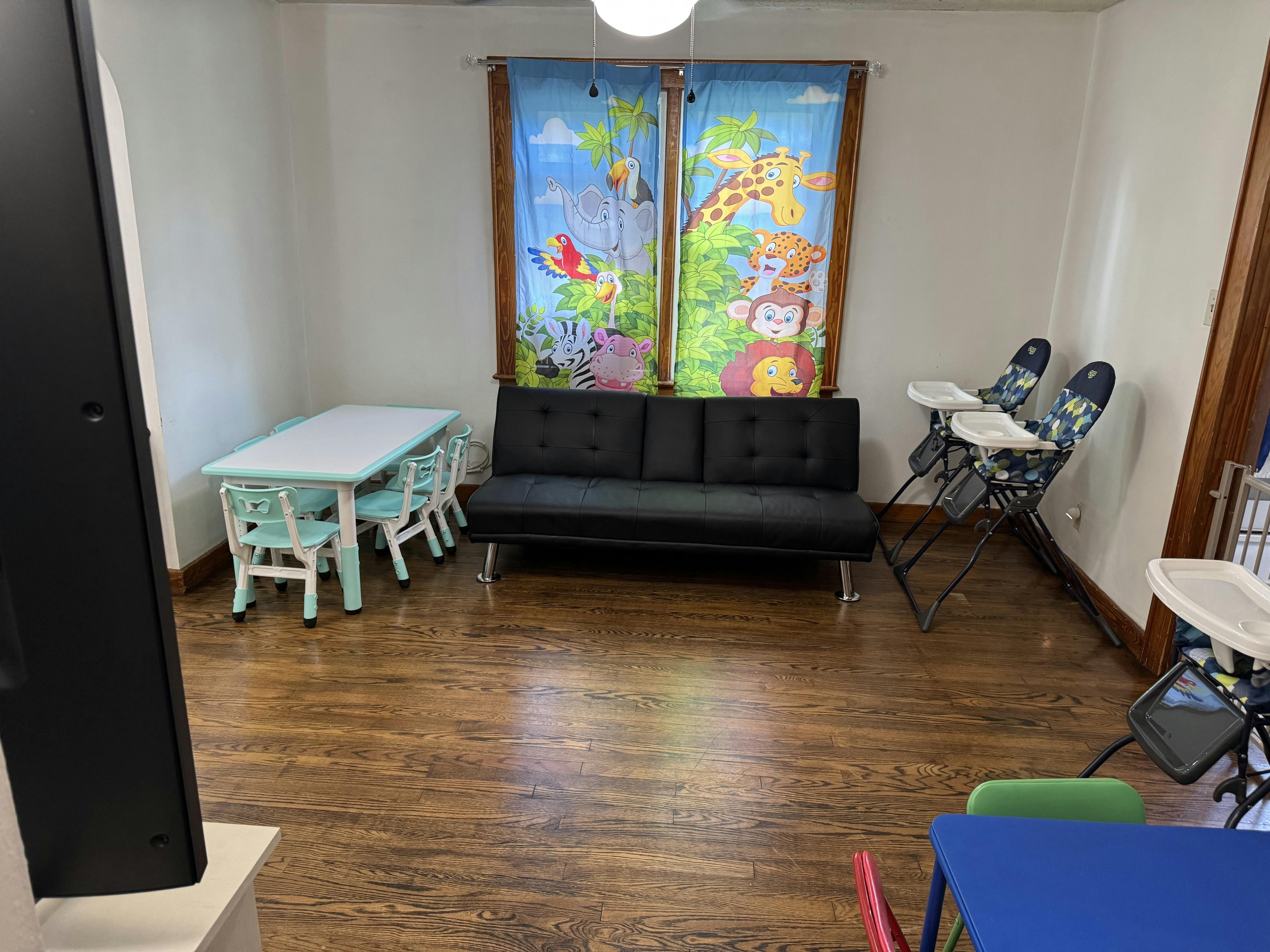 Room with a black sofa, small table with chairs, and high chairs