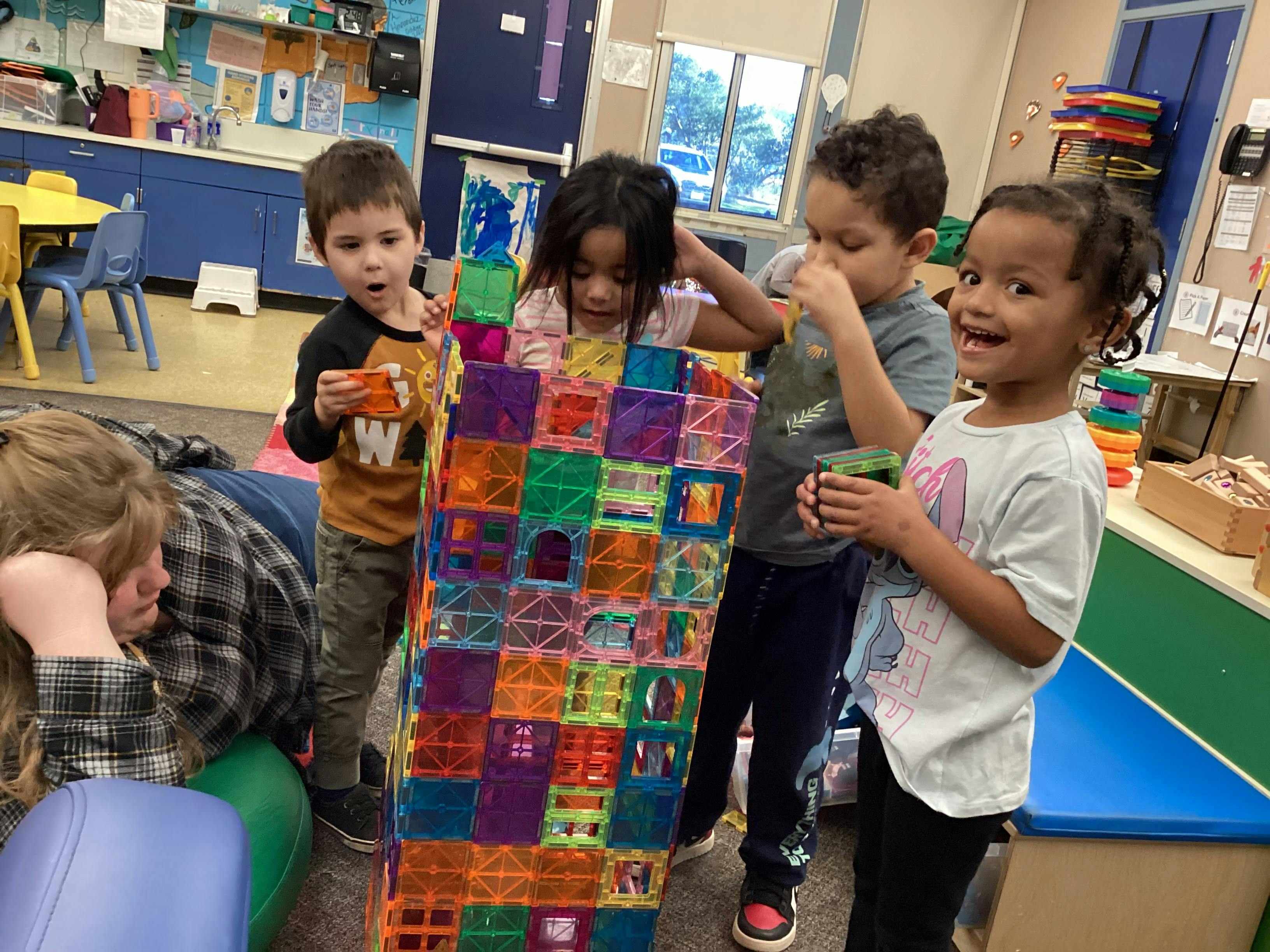 Group of children building a tall tower with colorful magnetic tiles