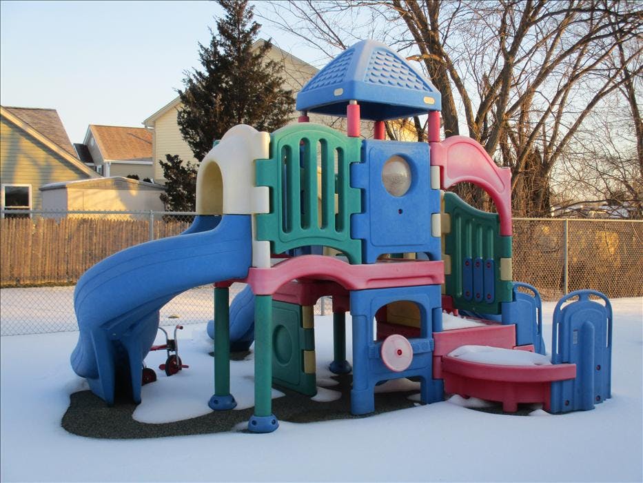 A colorful plastic playground structure with a slide on a snow-covered ground