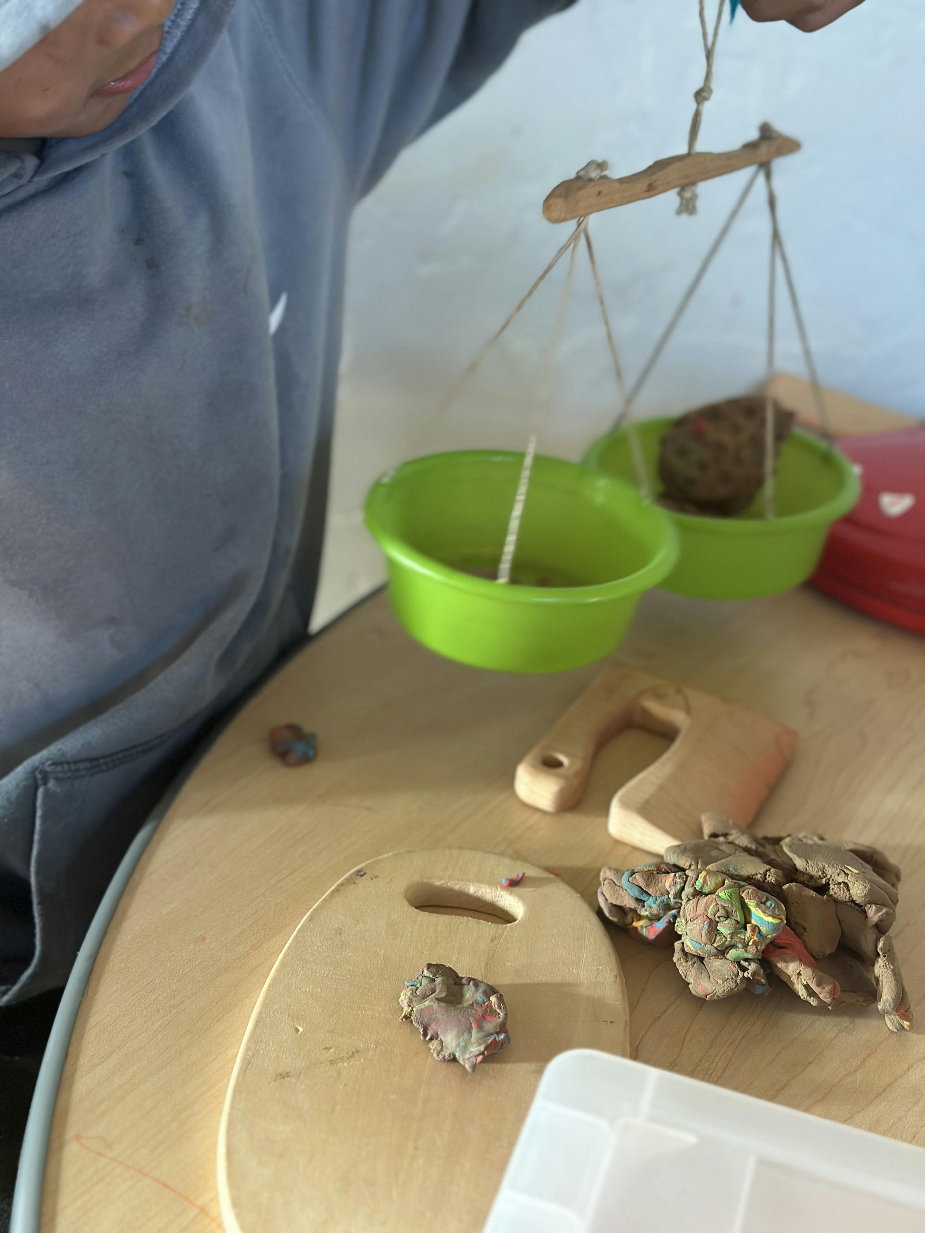 Child playing with modeling clay and a hanging scale