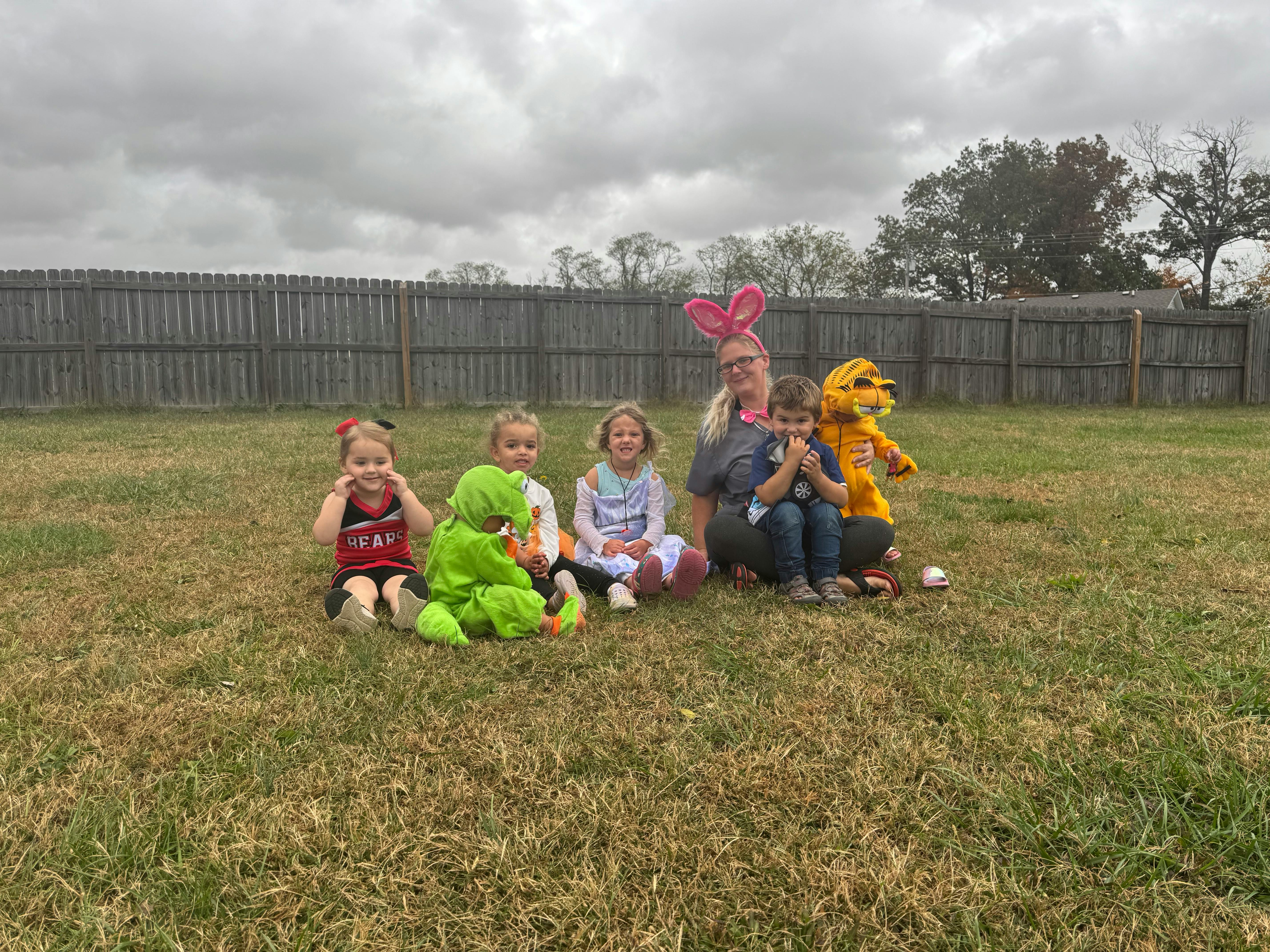 Adult and children in costumes sitting on grass