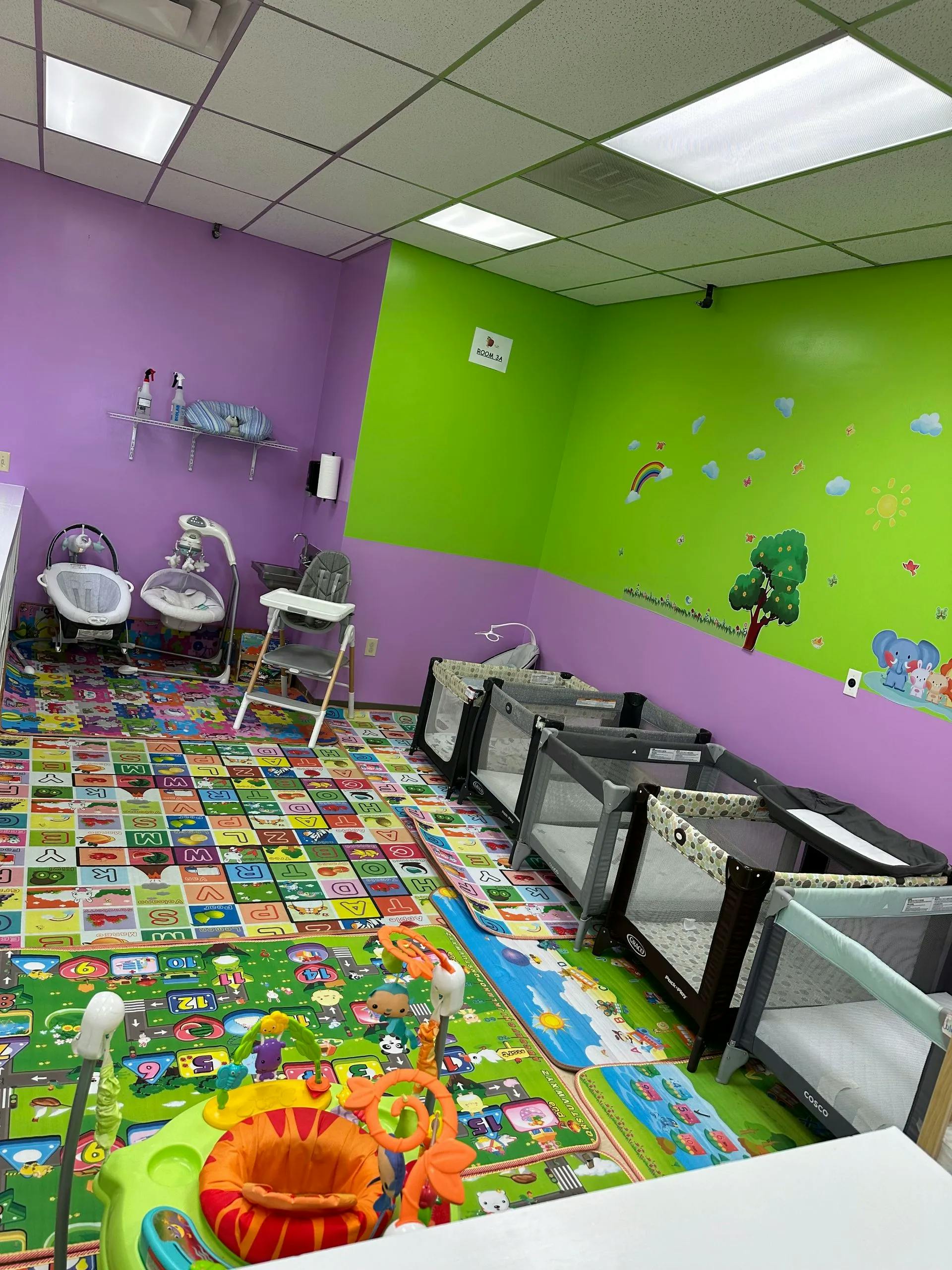 Nursery room with multiple cribs, play mats, and baby equipment