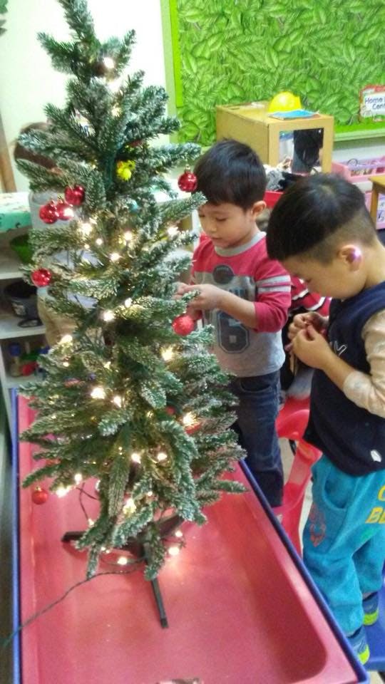 Two children decorating a small Christmas tree