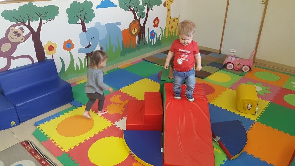 Two children playing on soft play equipment in a room