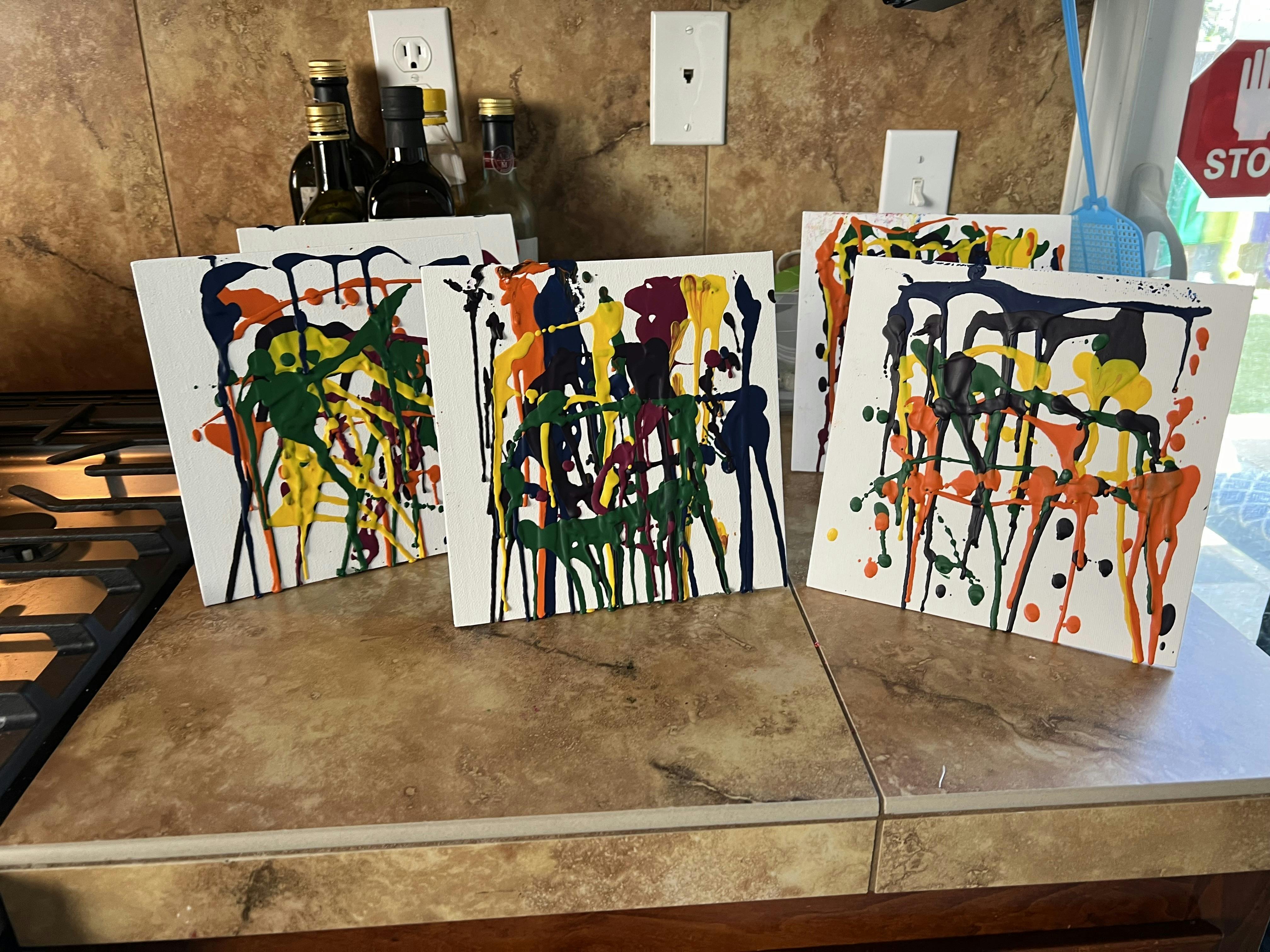 Multiple white canvases with colorful drip painting art