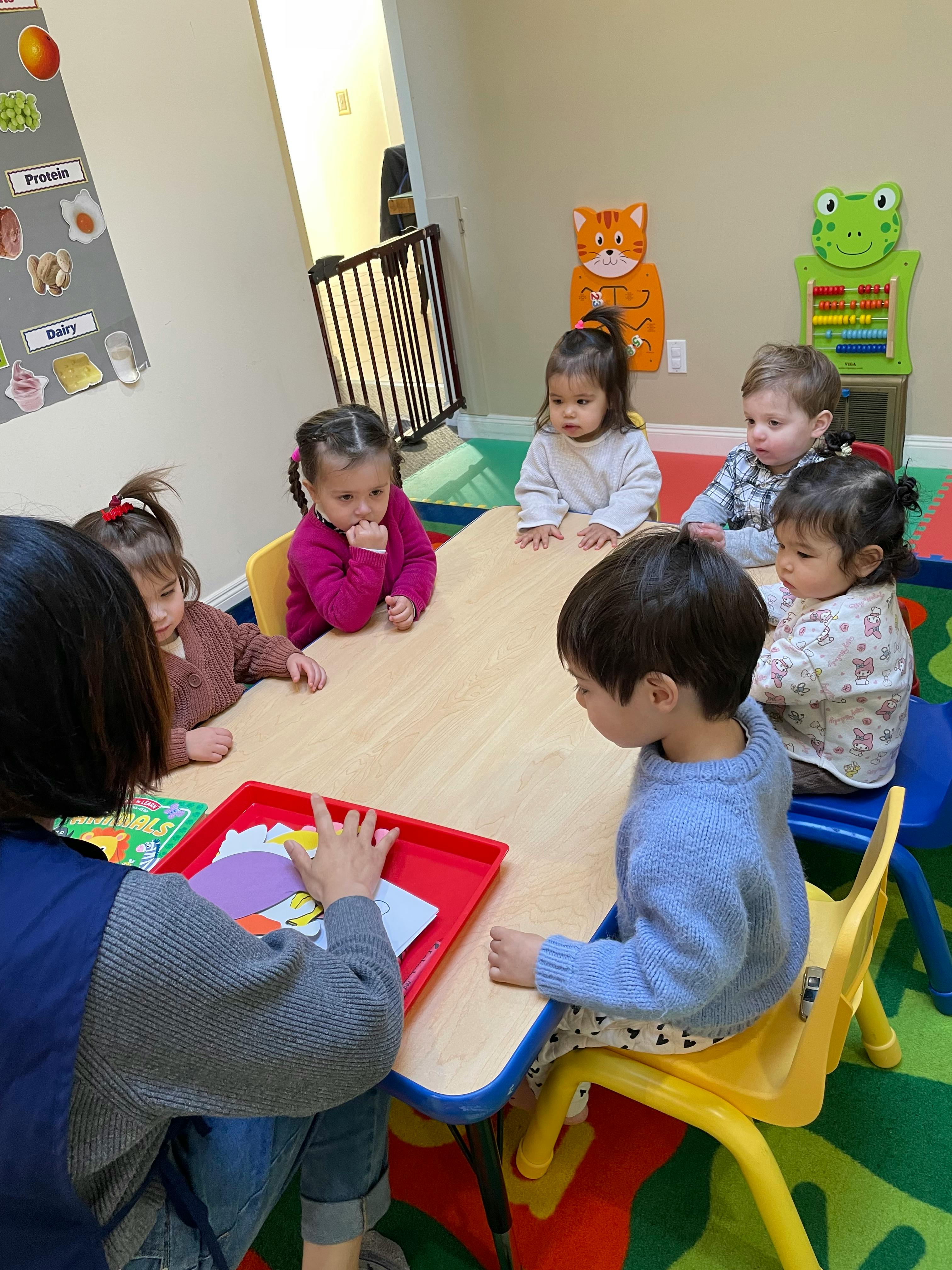 Adult and children sitting at a table in a classroom