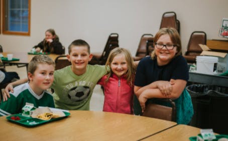 Four children sitting at a table in a cafeteria