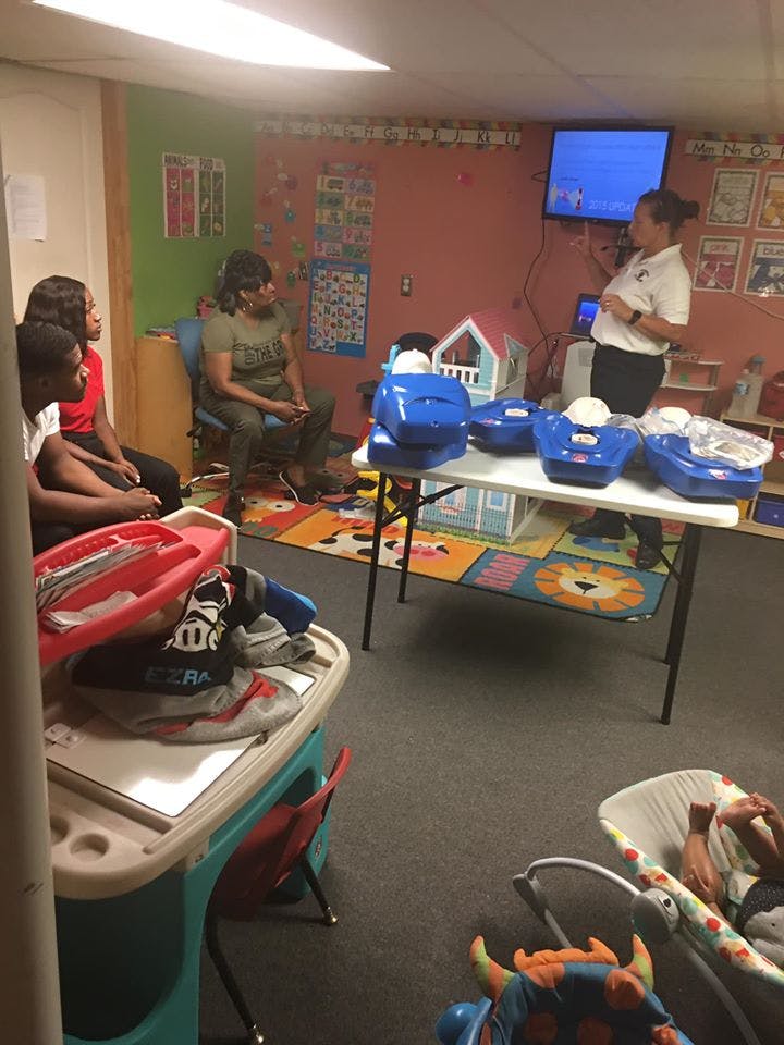 Person presenting to a group of people in a room with baby equipment