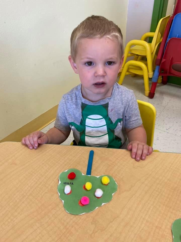 Child sitting at a table with a craft project