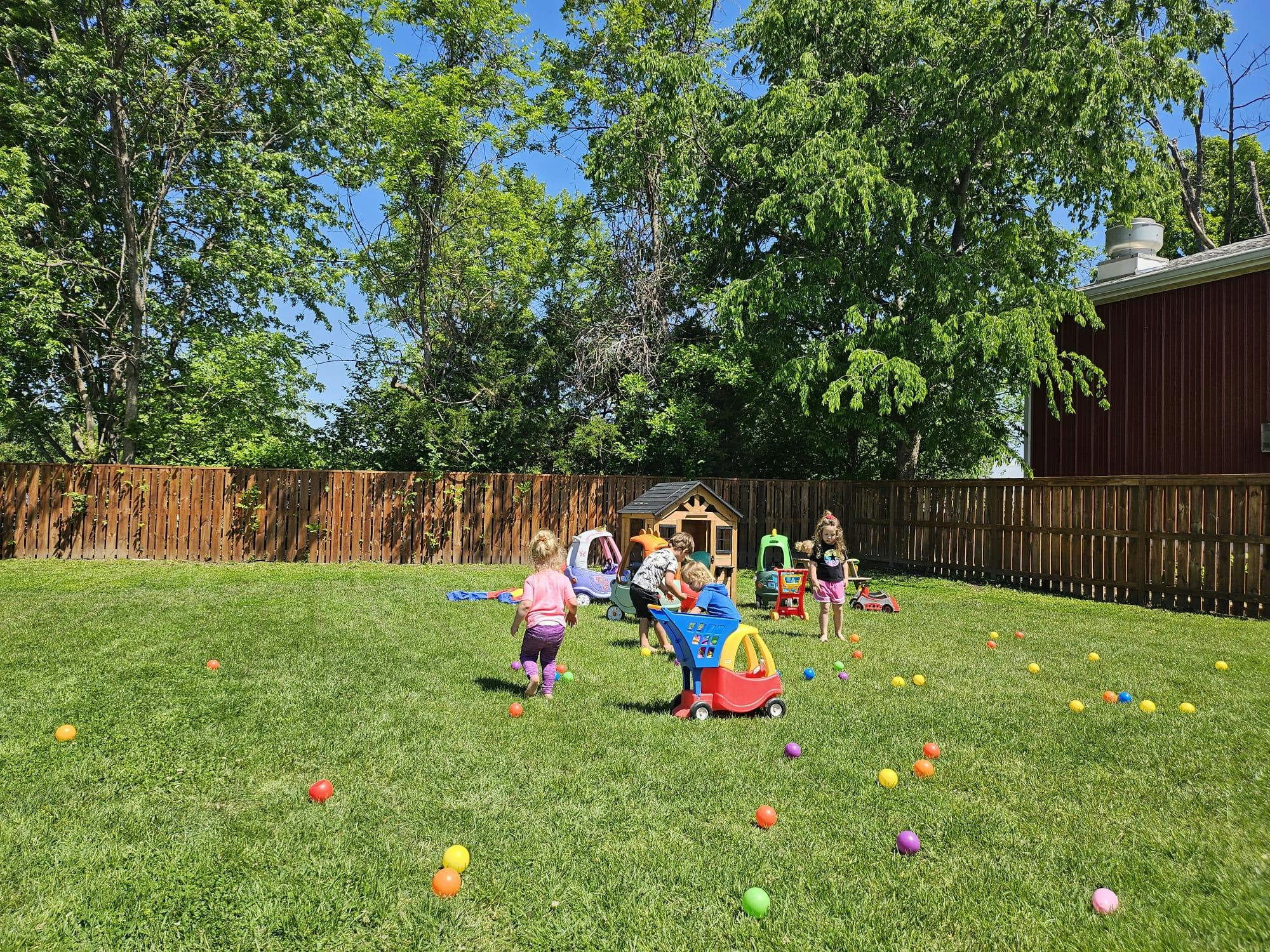 Children playing with toys in a grassy backyard