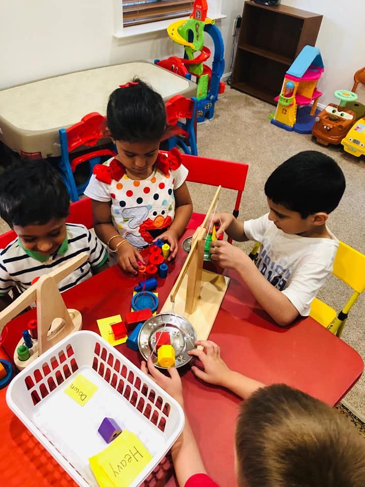 Three children playing with toys at a red table