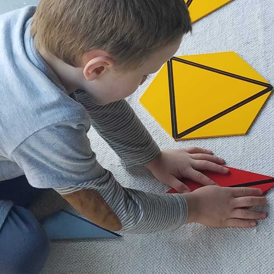 Child playing with geometric shapes on the floor