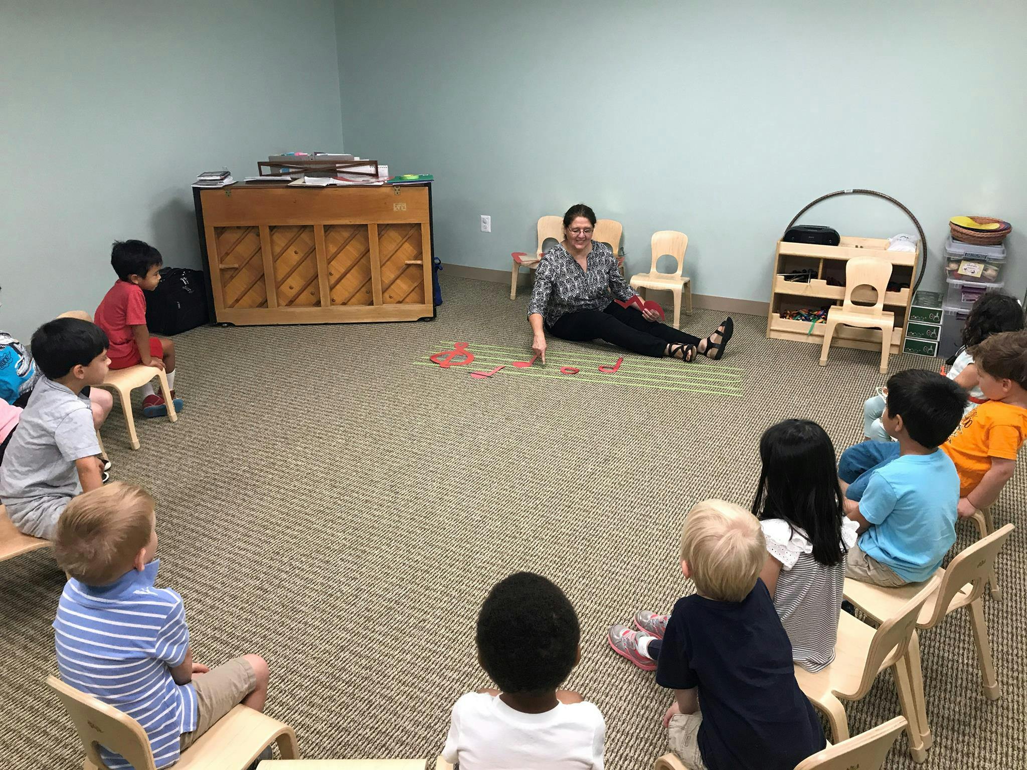 Person sitting on floor with children in a classroom