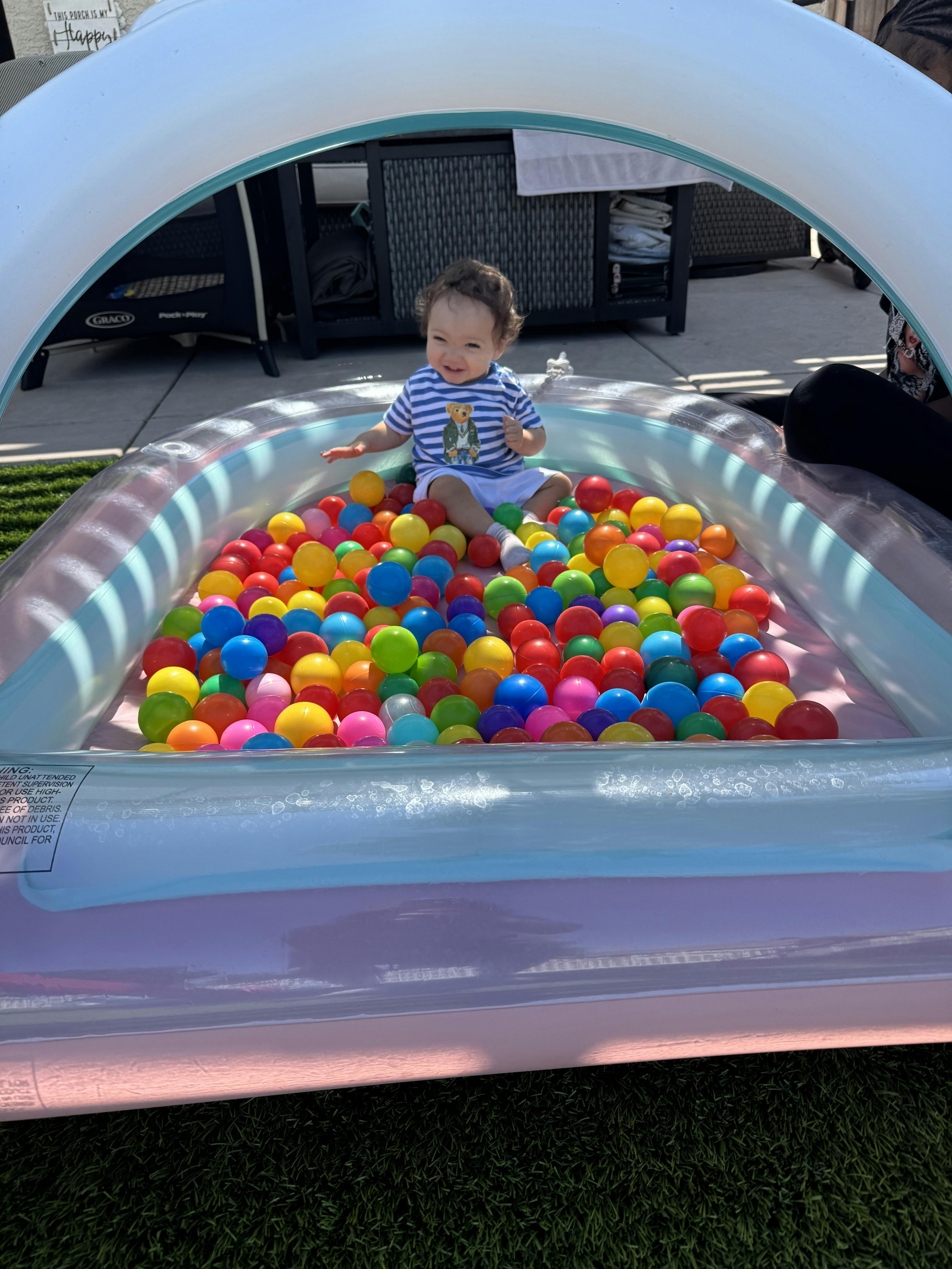 Child sitting in an inflatable ball pit filled with colorful plastic balls