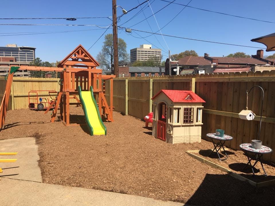 Outdoor playground with wooden playset, slide, and playhouse