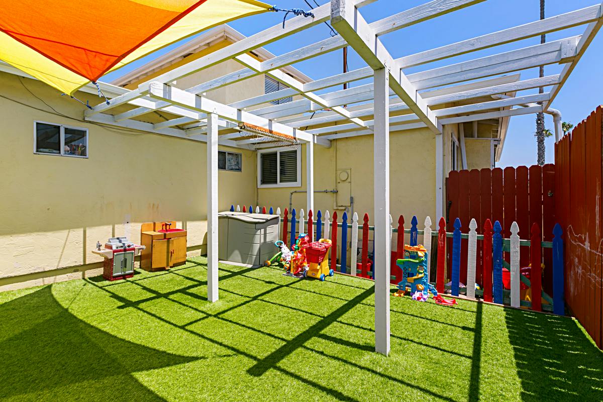 Outdoor play area with artificial turf and colorful fence