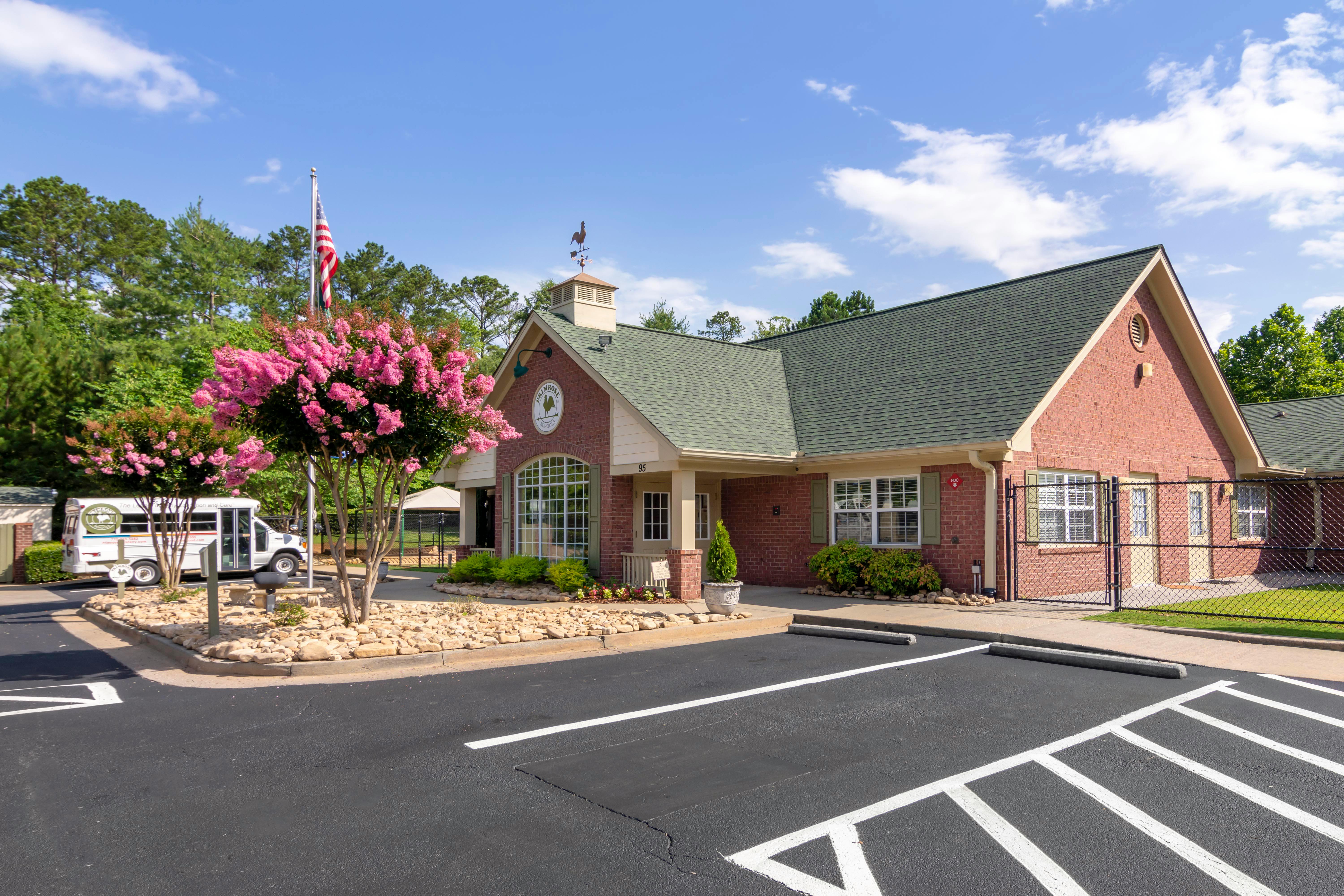 Brick building with green roof, small bus, and pink flowering trees