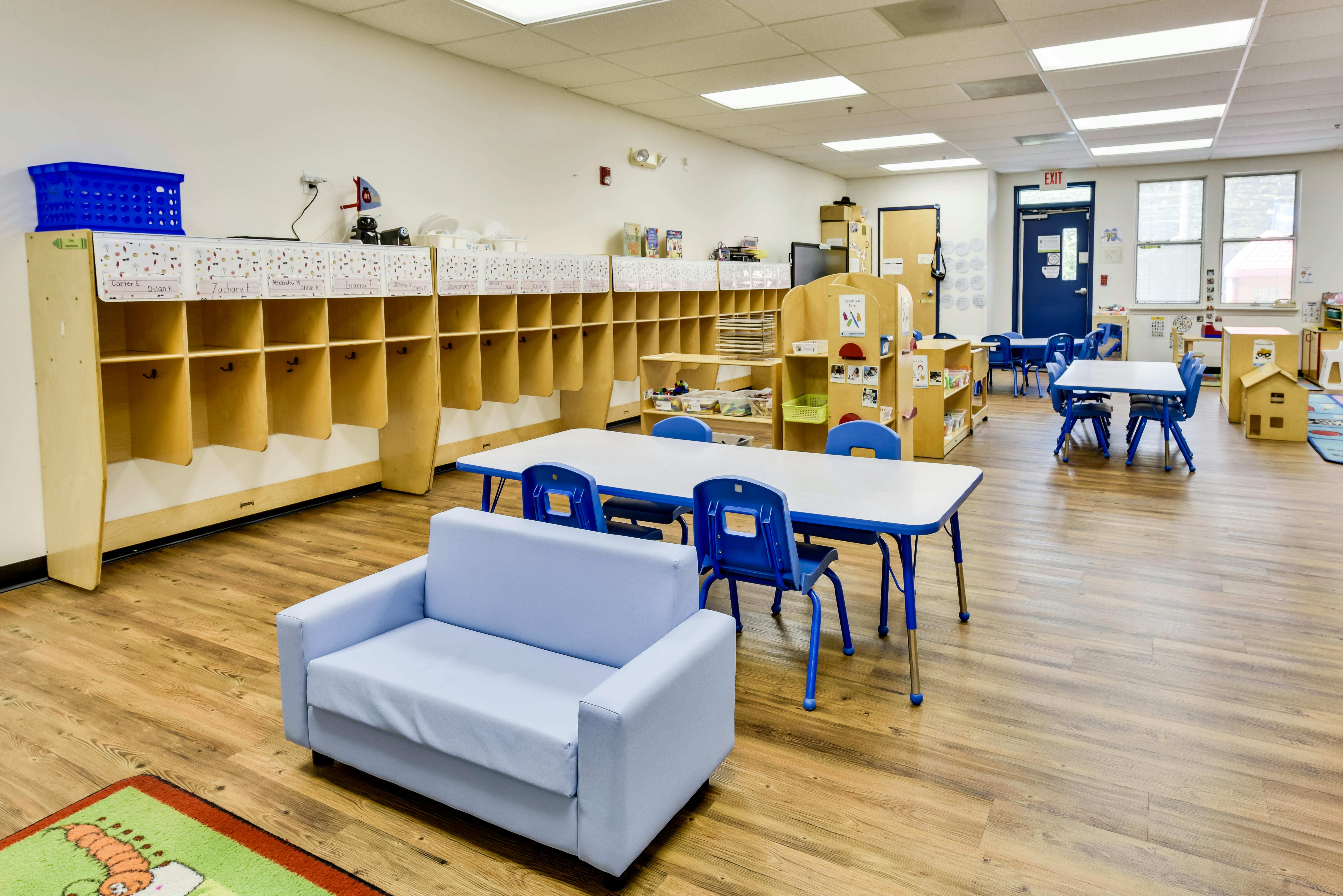 Empty classroom with child-sized tables, chairs, and cubbies