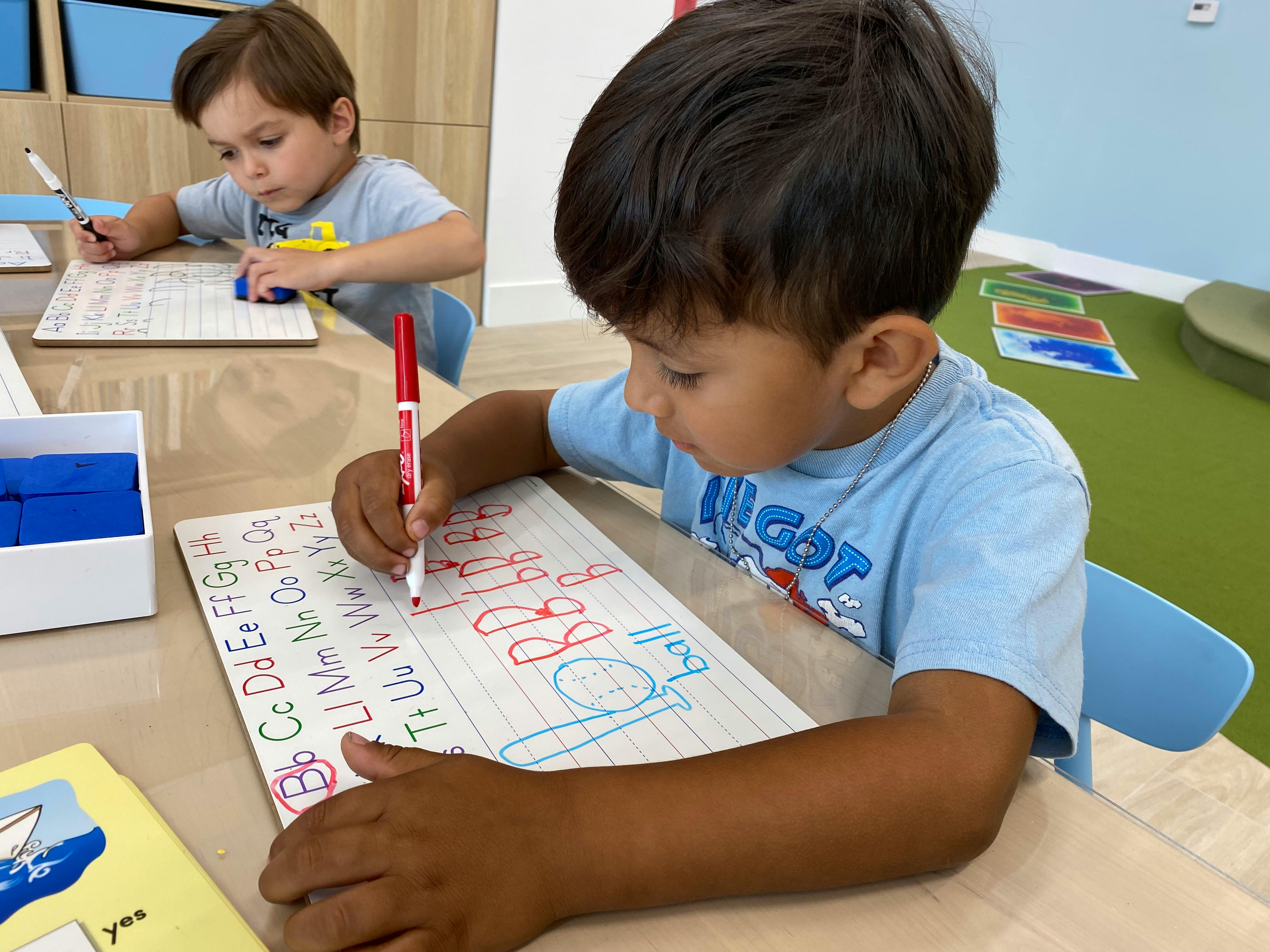 Child writing letters on a paper with a red marker