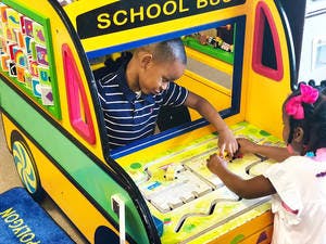 Two children playing in a toy school bus
