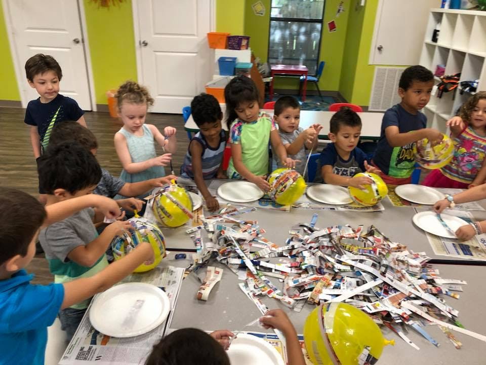 Children making crafts with shredded paper and yellow balloons