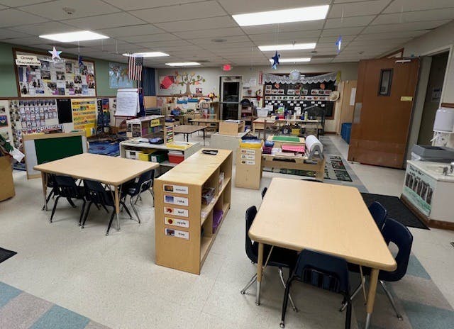 Classroom with small tables and chairs, shelves, and decorations on the walls