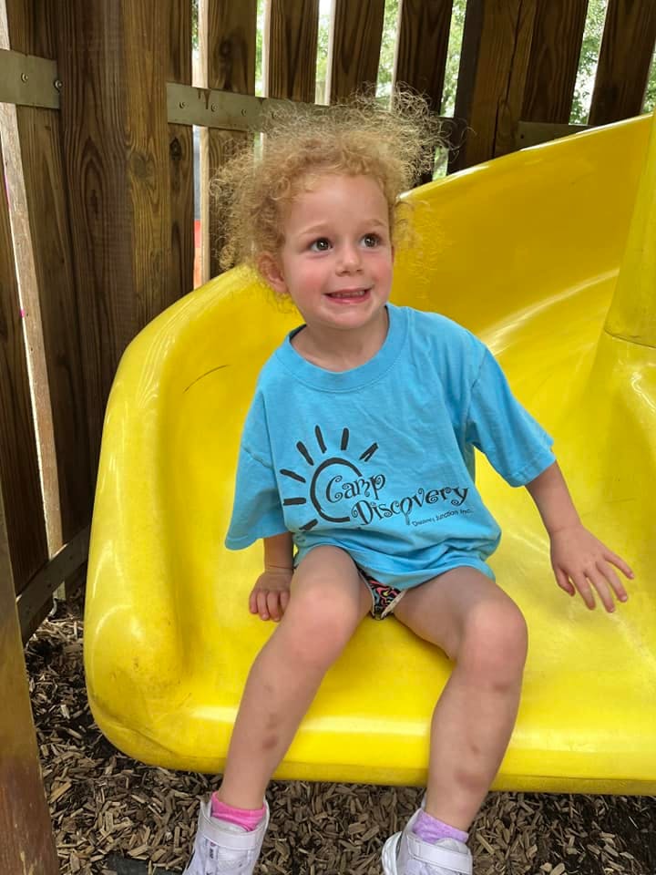 Child sitting on a yellow slide