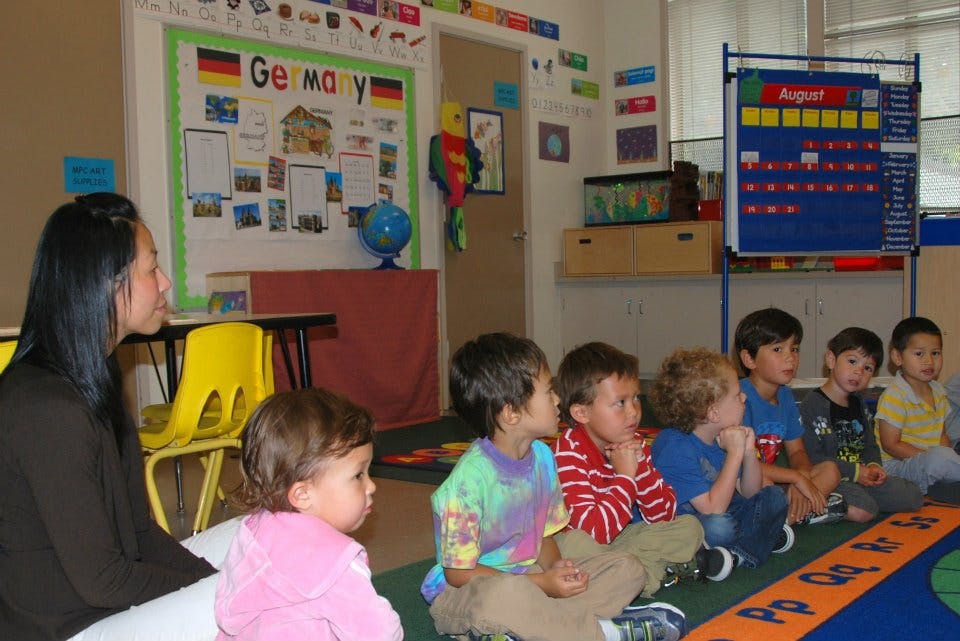 Adult and children sitting on the floor in a classroom